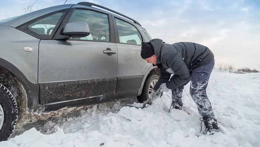 Schneeschaufel für filigrane Arbeiten Ein Mann befreit mit einer kleinen Schneeschaufel seinen eingeschneiten Wagen aus einer Schneewehe