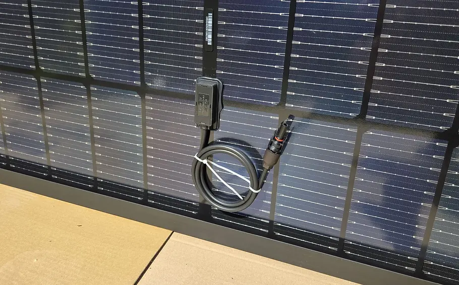 Rückseite eines Solarmoduls mit sichtbarem MC4-Stecker.