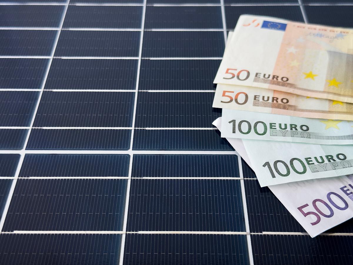 Fünf große Euroscheine (50, 100, 500) liegen auf einem dunkelblauen Solarpanel