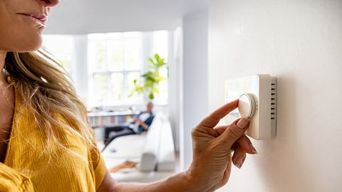 Frau dreht am Regler für Klimagerät - Foto: iStock / andresr