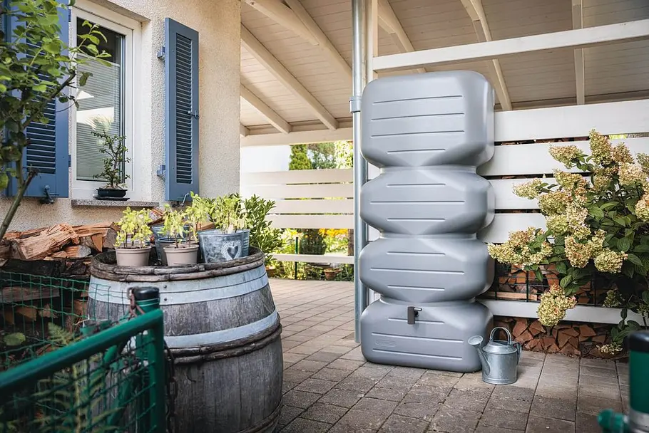 Oberirdische Regenspeicher Moderner oberirdischer Regenspeicher an einer Hauswand zur Sammlung von Regenwasser für die Gartenbewässerung.