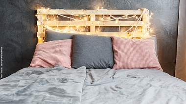 Mit Lichterketten sieht das DIY-Bett noch gemütlicher aus. - Foto: iStock / KatarzynaBialasiewicz