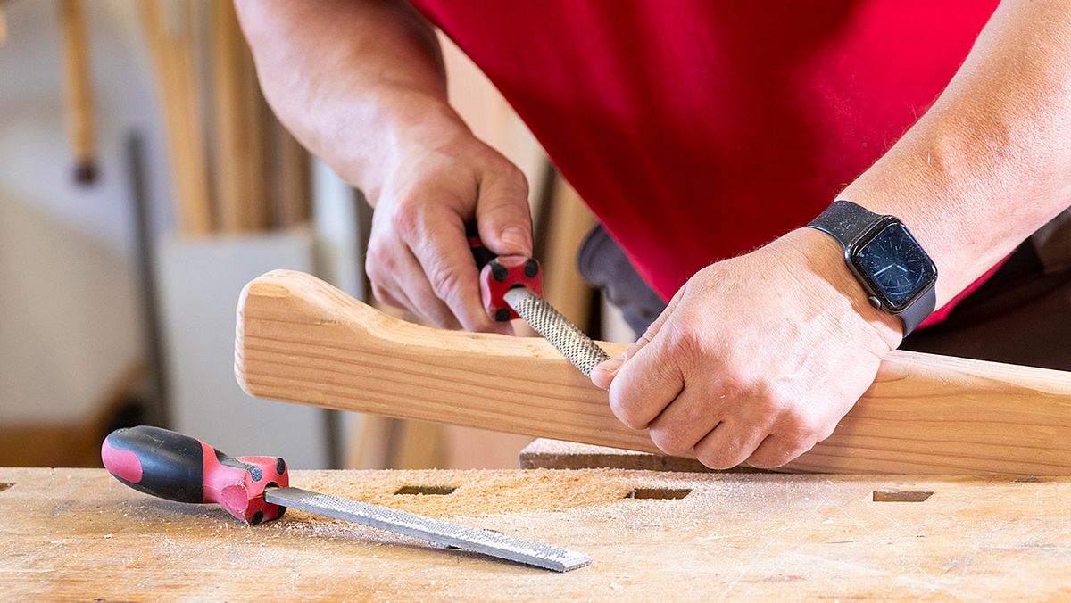 Nahaufnahme von einem länglichen Holzstück, das gefeilt wird.