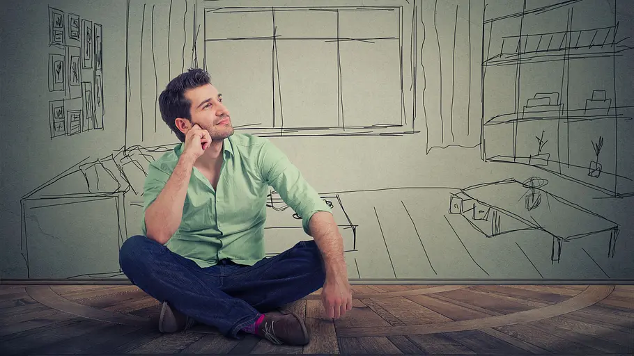 Wohnung einrichten mit Feng Shui Ein Mann im Schneidersitz denkt darüber nach, wie er seine Wohnung mit Feng Shui einrichten kann