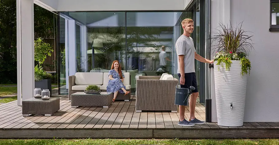 Garantia Bewässerung Design-Regenspeicher an einer Hausfassade speichert Regenwasser und dient gleichzeitig als dekoratives Gestaltungselement im Garten.