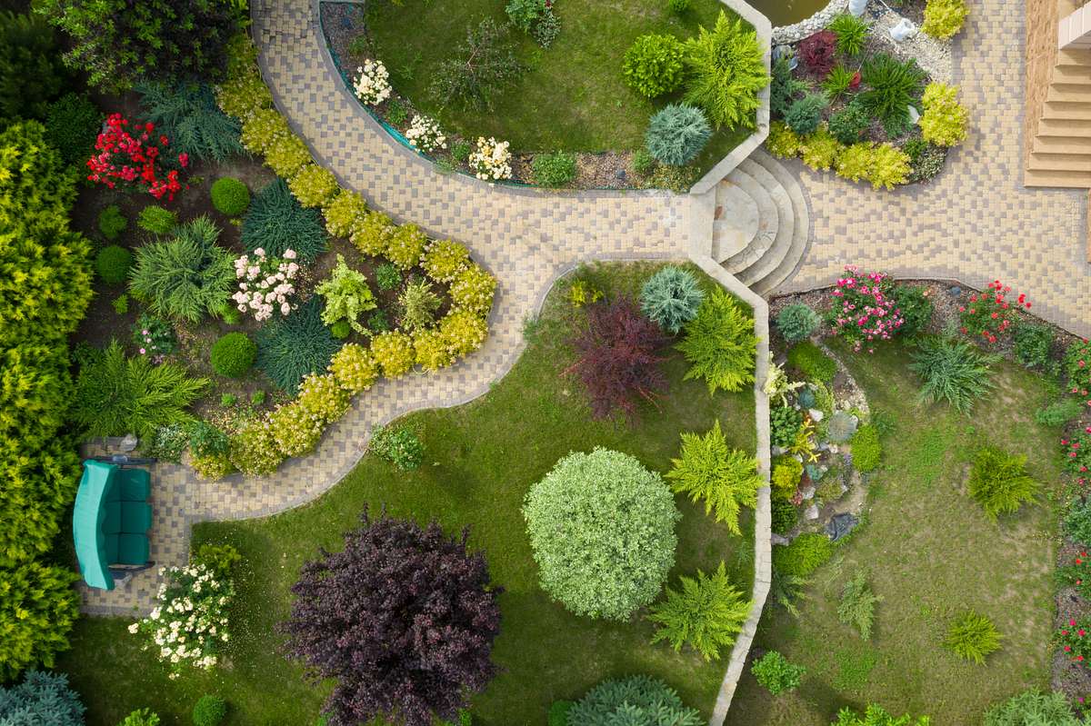 Ein schön gestalteter Garten aus der Vogelperspektive mit Rasenflächen und Pflanzen