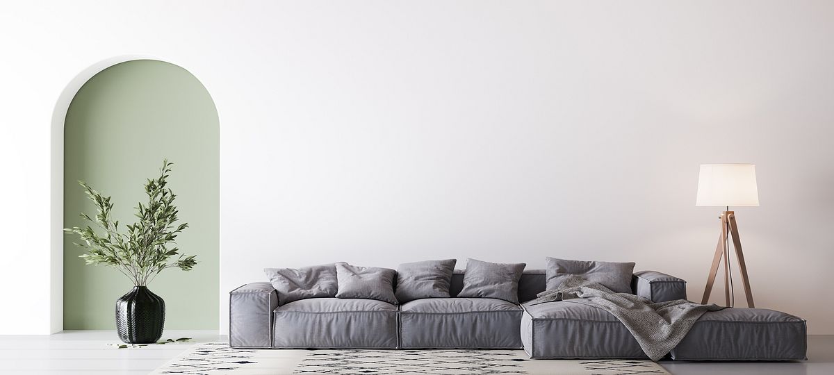Ein gemütliches Sofa vor einer weißen Wand, von der ein Teil in Salbeigrün gestrichen ist
