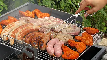 Ein Grill mit diversen Fleisch- und Wurstsorten auf dem Rost. - Foto: Archiv