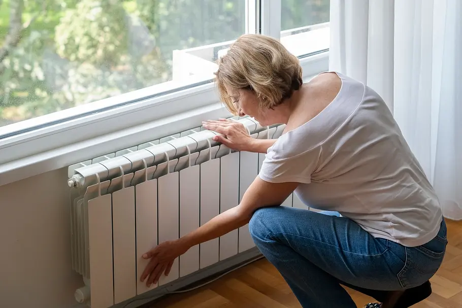Heizkörper-Frau-Wohnung Eine Frau berührt einen modern aussehenden Wohnungs-Heizkörper