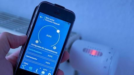 Ein Smartphone mit einer App ist im Vordergrund, dahinter sieht man einen Heizkörper. - Foto: Imago/ Kosecki