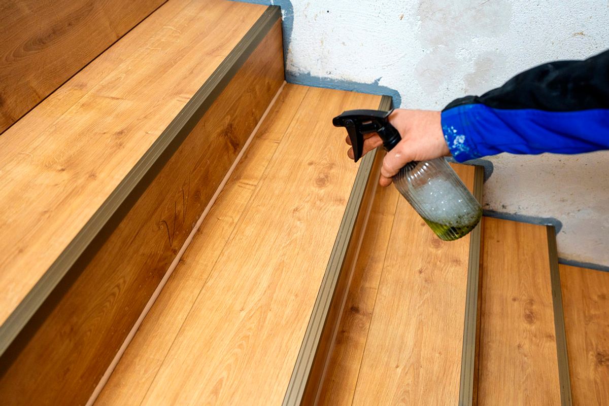 Mit einer Sprühflasche wird die Holztreppe besprüht