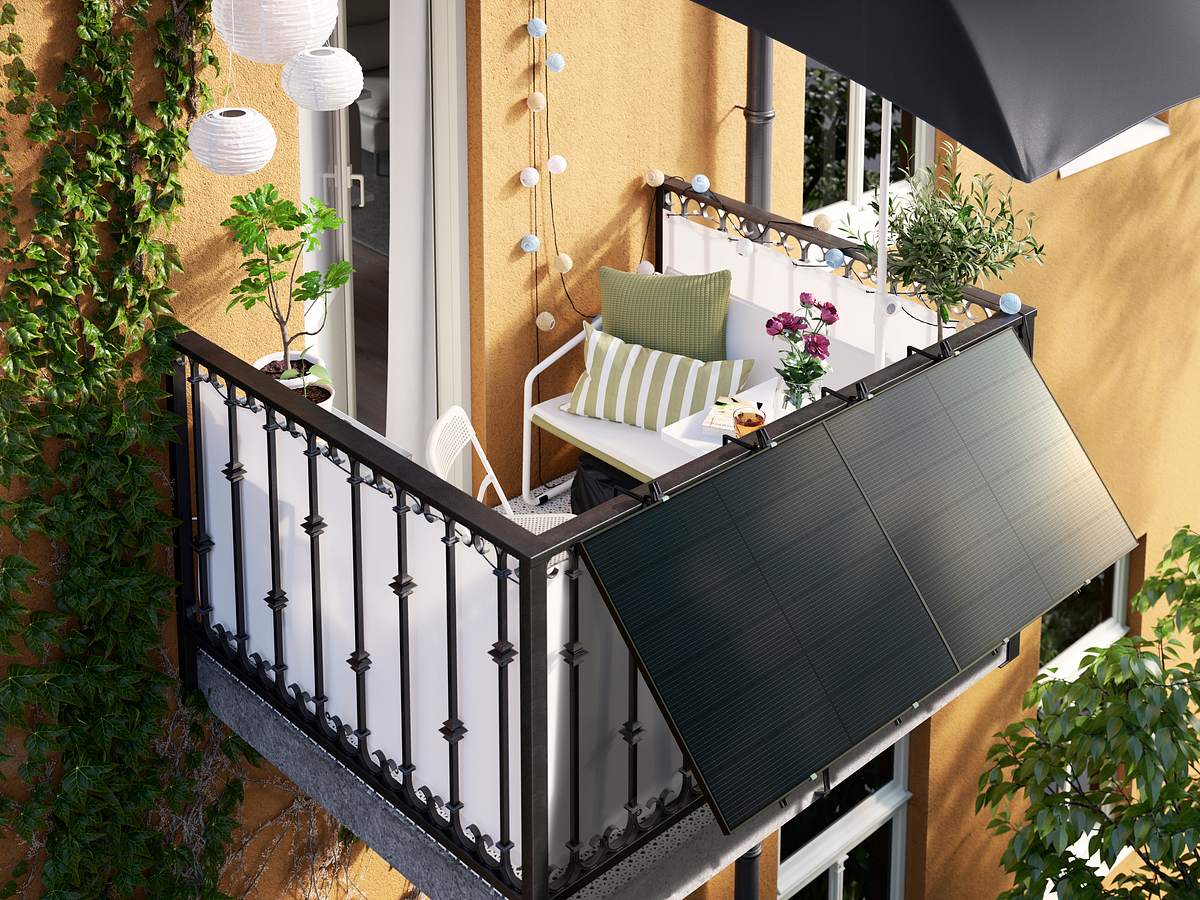 Solarpanels eines Balkonkraftwerkes angebracht an einem gemütlichen Balkon, der aus einem gelben Haus ragt