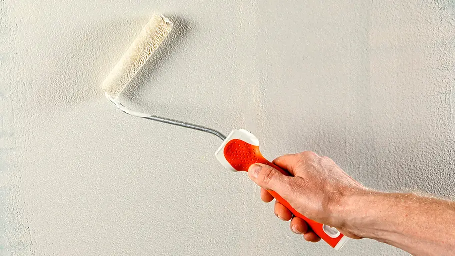 Spachtelmasse Mit einer kleinen Farbrolle wird frische, weiße Spachtelmasse auf einer Wand verteilt und geglättet.
