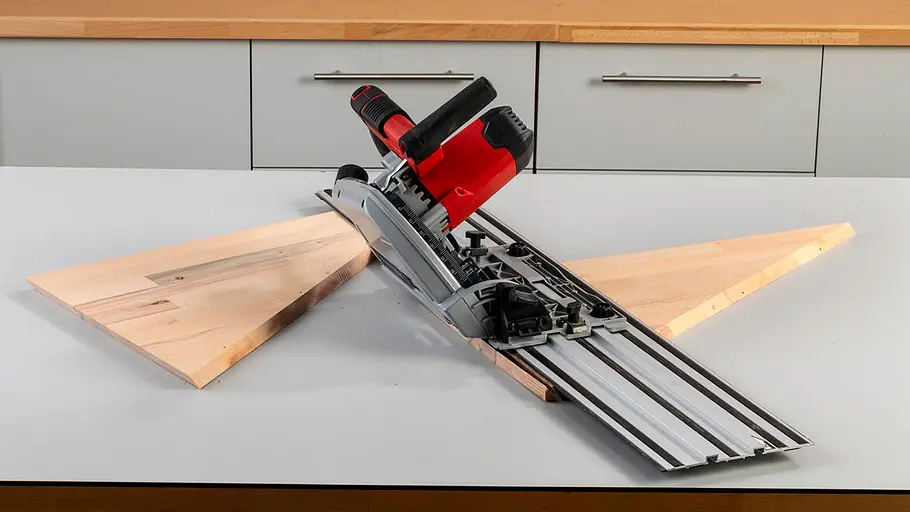 Verdrehter Hocker Eine Tauchsäge mit Führungsschiene liegt auf zwei dreieckig zugeschnittenen Holzplatten auf einer Werkbank.