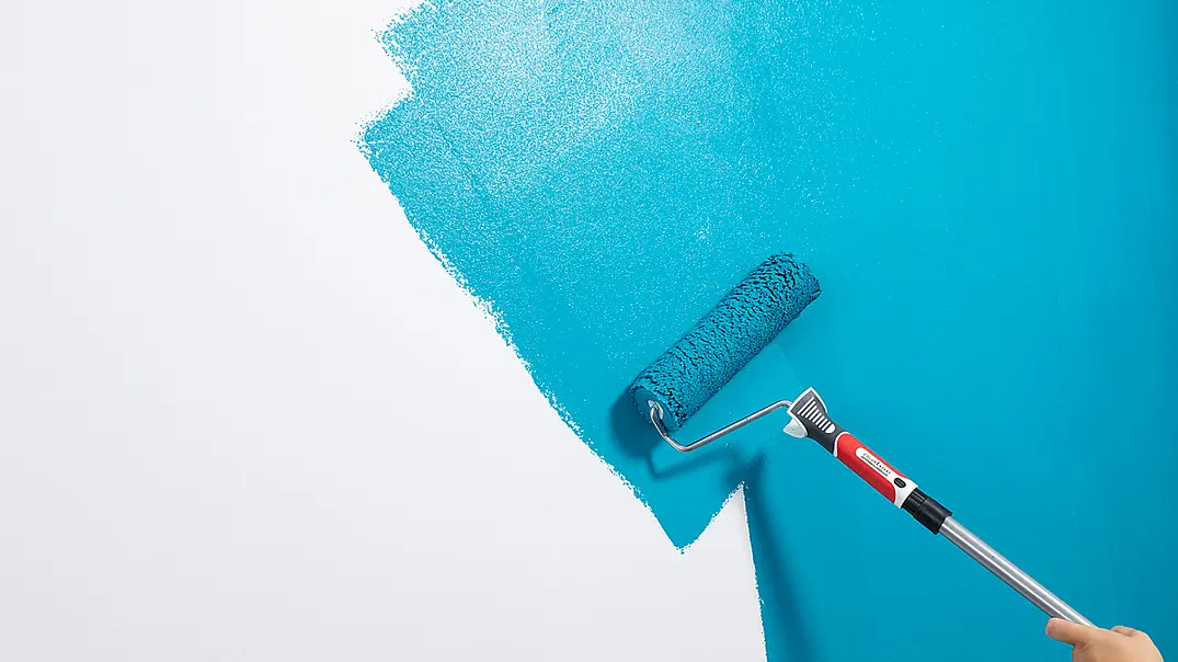 Mit einer Farbrolle wird hellblaue Farbe auf eine noch zur Hälfte weißen Wand aufgetragen. - Foto: sidm / CK Mit einer Farbrolle wird hellblaue Farbe auf eine noch zur Hälfte weißen Wand aufgetragen. - Foto: sidm / CK