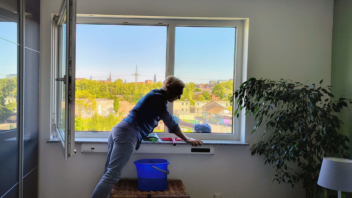 Mann poliert mit Baumwolltuch ein Fenster streifenfrei