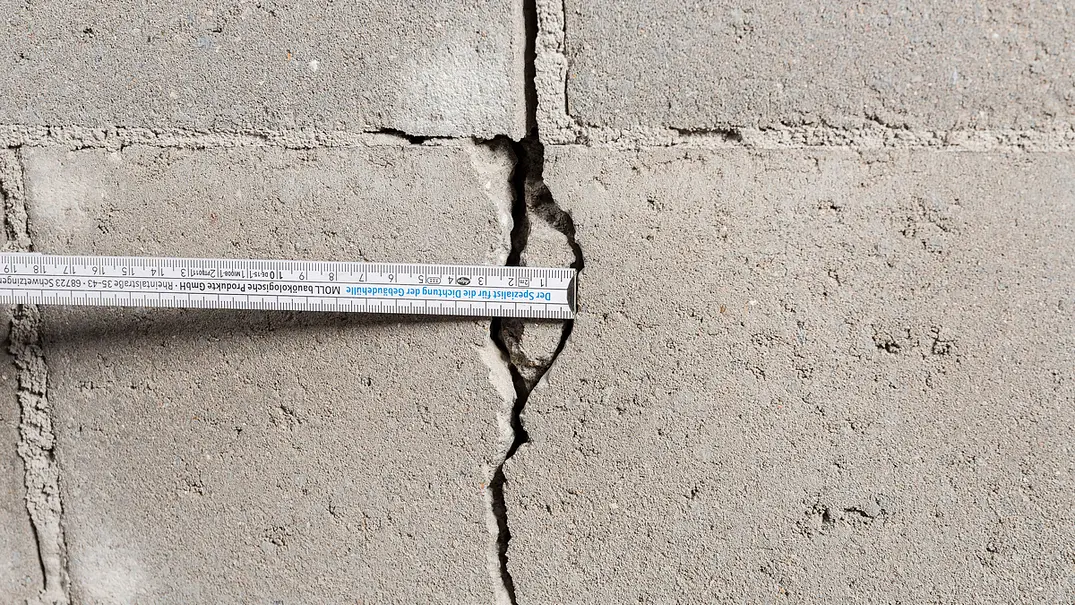 Ein Riss im Mauerwerk wird mit einem Zollstock vermessen, eine Schraube ist direkt im Bereich des Risses platziert. - Foto: Hersteller / Moll/pro clima Ein Riss im Mauerwerk wird mit einem Zollstock vermessen, eine Schraube ist direkt im Bereich des Risses platziert. - Foto: Hersteller / Moll/pro clima