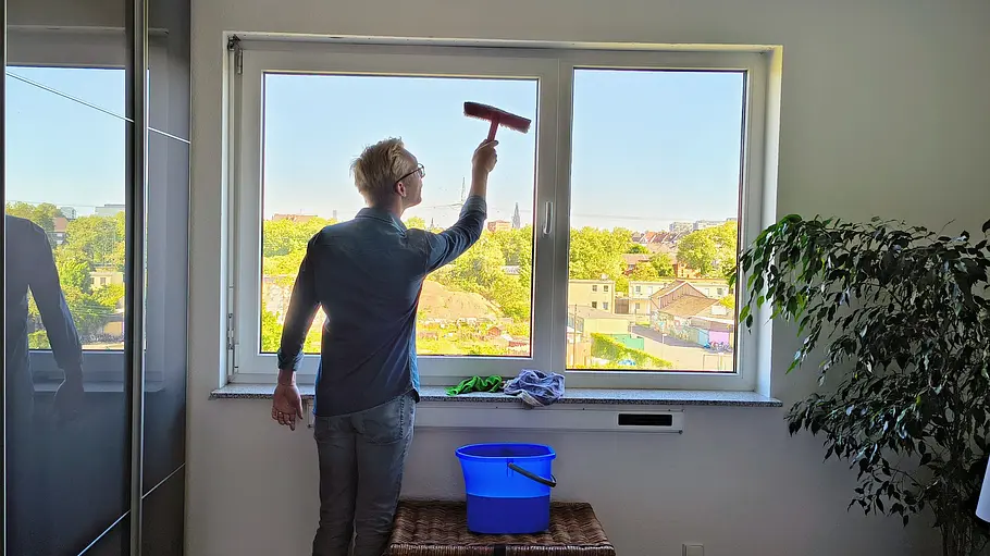 Ein Mann trägt mit dem Einwascher Seifenlauge auf eine Fensterscheibe auf