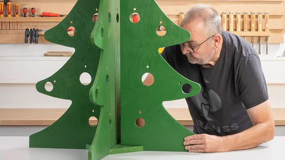 Der Weihnachtsbaum aus Holz wird ineinander gesteckt.