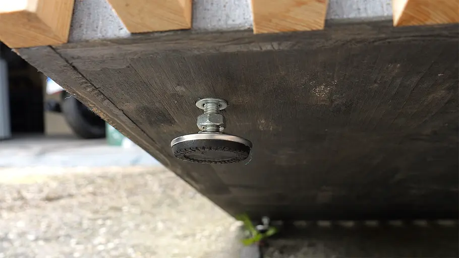 Paketbox Ein höhenverstellbarer Metalluß ist an der dunklen Unterseite der hölzernen Paketbox befestigt.