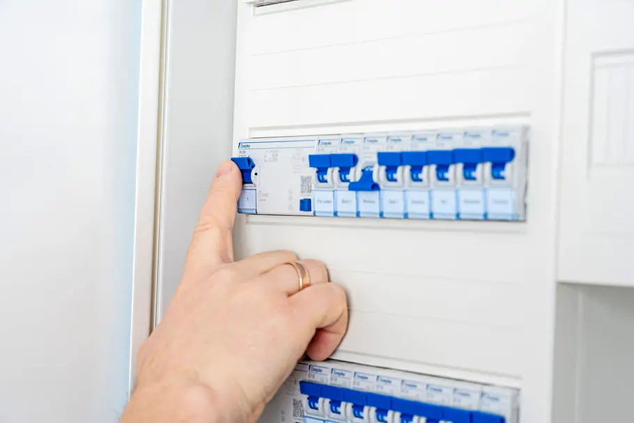 Smarte Beschattung Hand schaltet einen Leitungsschutzschalter im Sicherungskasten ein oder aus. Die Elektroverteilung ist Teil einer Smart-Home-Installation für die Gebäudeautomation.