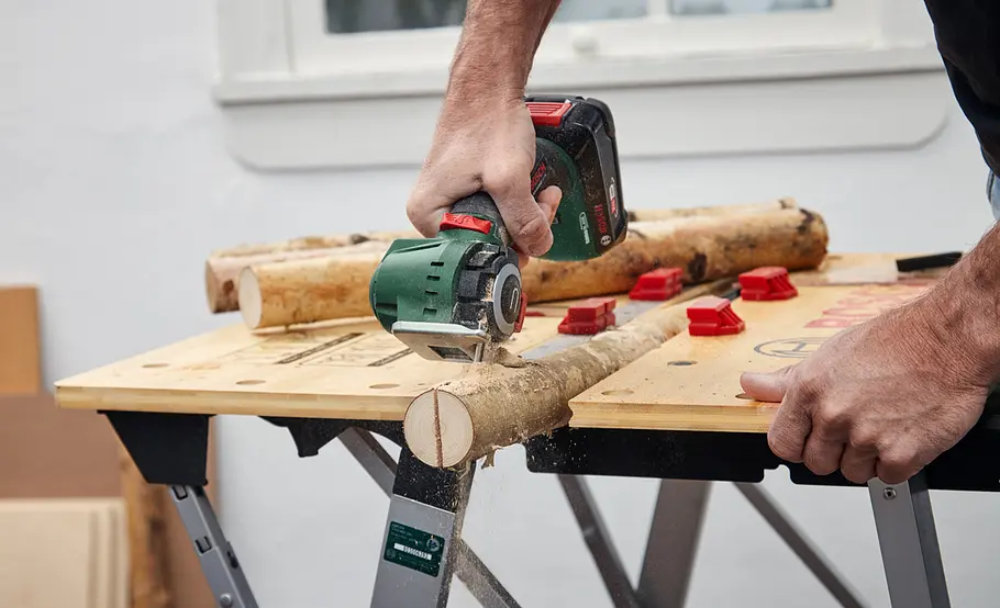 Winterquartier für Igel bauen Birkenstämme werden mit Säge in zwei Hälften geteilt