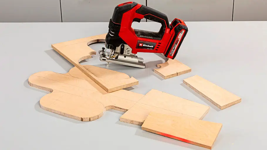 Katzen-Kratzbrett zuschneiden Eine Stichsäge liegt auf zugesägten Holzplatten, darunter ein großes Holzelement in Form eines Kaktus für das Kratzbrett.