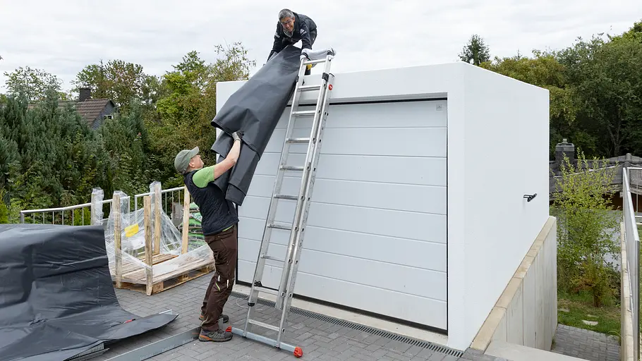 Folie wird auf Garage gereicht