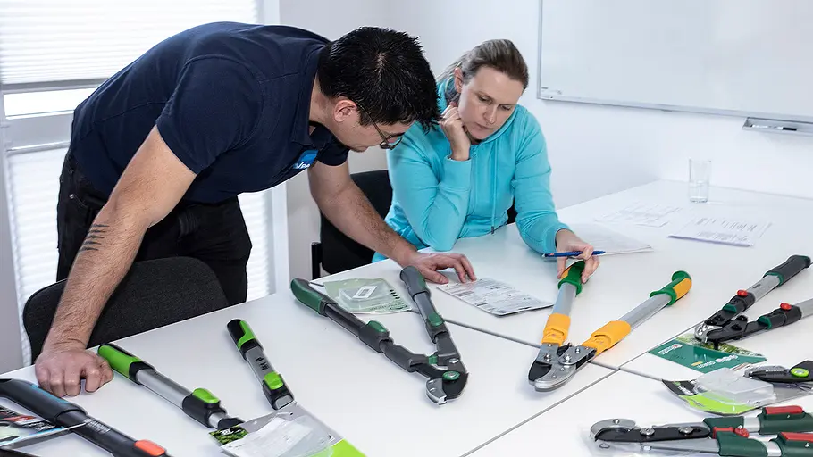Astscheren-Test Begutachtung Zwei Personen begutachten Astscheren an einem Tisch, prüfen Unterlagen und vergleichen verschiedene Modelle.