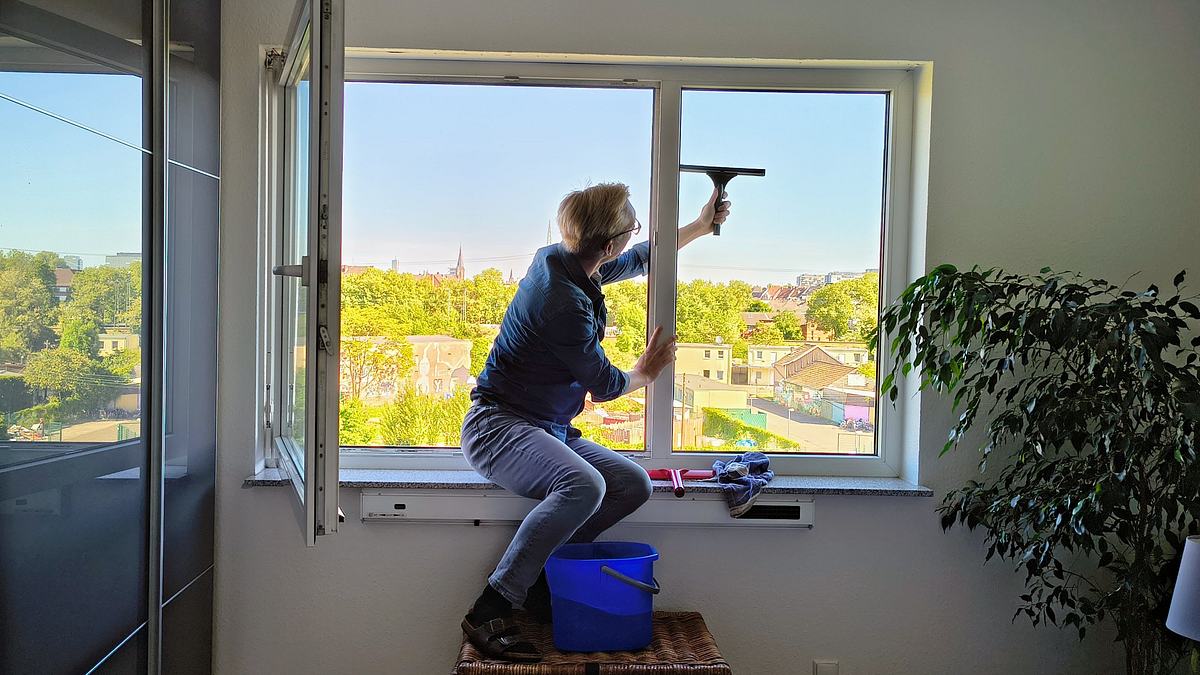 Mann fährt mit dem Abzieher über die Außenseite des Fensters