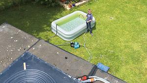 Kind befüllt Pool mit Wasserschlauch im Garten - Foto: sidm / DW, PB