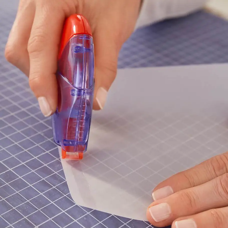 Weihnachts-Windlicht: Funkelndes Sternen-Glas Mit einem Kleberoller wird Transparenkleber am Rand des Papierbogens aufgetragen.