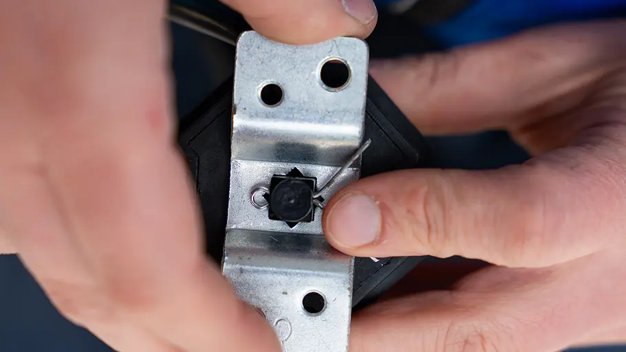 Markisenmotor: Lager sichern Zwei Hände sichern das Lager des Markisenmotors mit einem Metallstift an einer silbernen Halterung.
