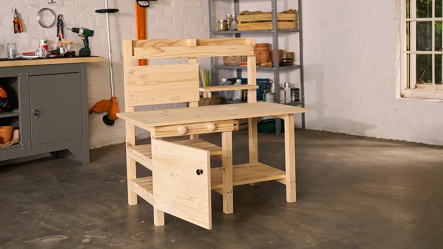Matschküche: Rahmen Der Rahmen der Matschküche steht mit montierter Arbeitsplatte, Seitenschrank, Regal und Knöpfen aus hellem Holz in der Werkstatt.