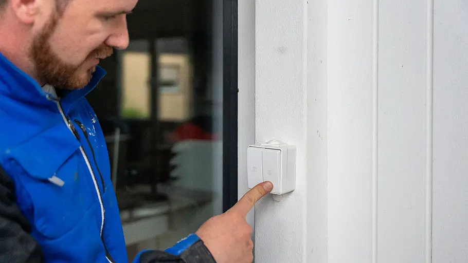 Steuerung Ein Mann drückt einen Kippschalter an der Wand, um die Steuerung der elektrischen Markise zu bedienen.