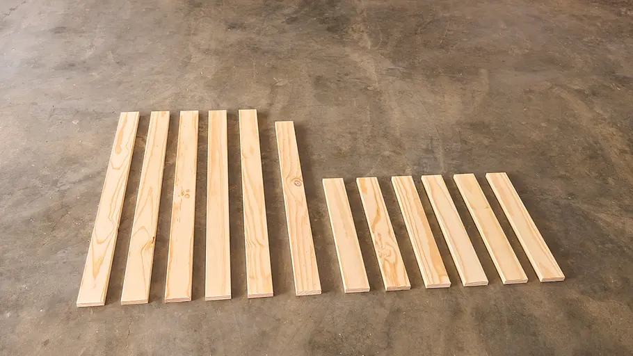 Matschküche: Sortierte Latten Mehrere zugeschnittene Holzlatten in verschiedenen Längen liegen ordentlich sortiert nebeneinander auf einem Betonboden.