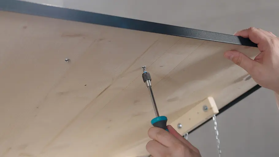 Paketbox Eine Person verschraubt mit einem Schraubendreher das Holz von innen mit dem Deckel einer halb geöffneten Paketbox.