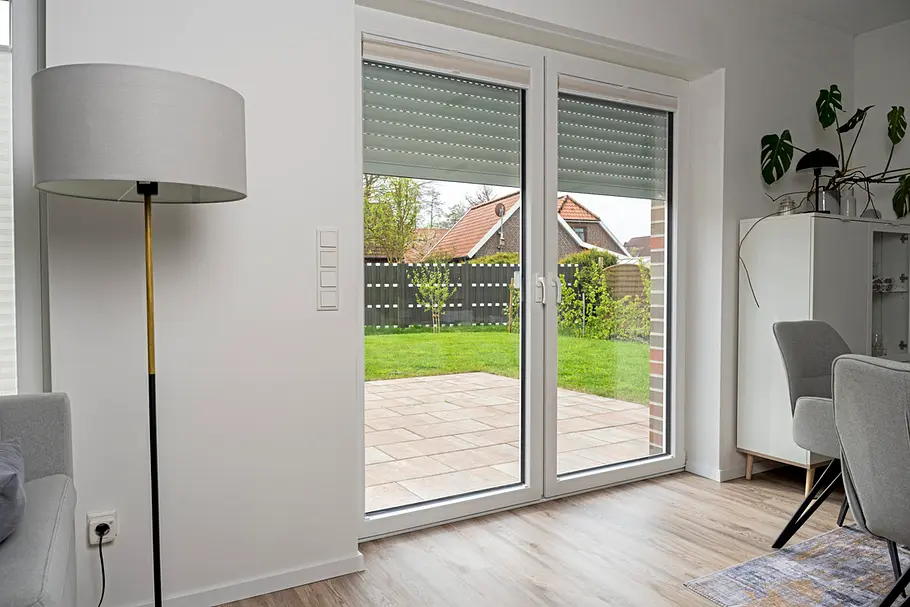 Smarte Beschattung Große Terrassentür mit teilweise heruntergelassenen Rollläden in einem modernen Wohnraum. Die Beschattung reguliert Tageslicht und Wärme im Innenbereich.