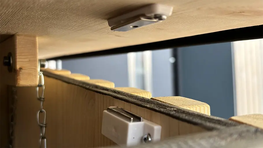 Paketbox Innenansicht einer Paketbox mit Magnetverschlüssen an Holzleisten und einer Metallkette an der Wand zur Stabilisierung.