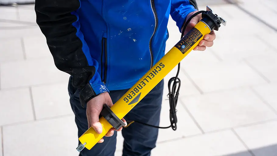Laufringadapter aufstecken Eine Person schiebt einen schwarzen Laufringadapter auf einen gelben Markisenmotor im Außenbereich.