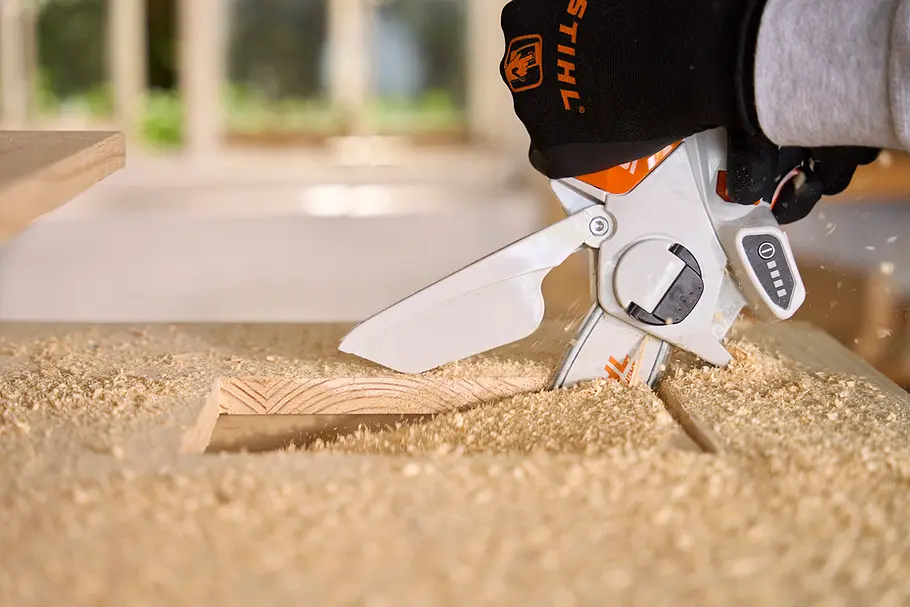 Matschküche: Waschbeckenöffnung Eine Person schneidet mit einer STIHL-Gehölzschneider eine rechteckige Öffnung in eine Holzplatte, um Platz für das Waschbecken zu schaffen.
