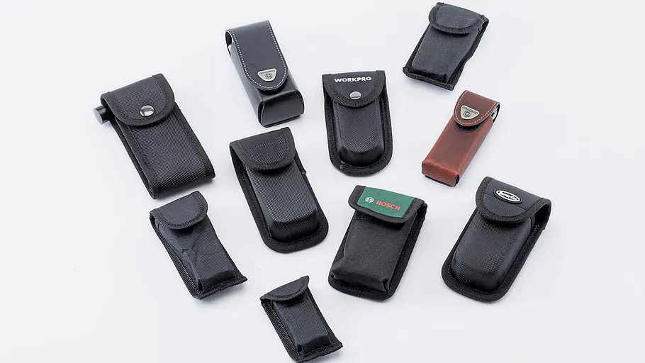 Multitool-Test Zehn verschiedene Multitool-Taschen aus Stoff und Leder liegen auf weißem Untergrund, teils mit Logos versehen.