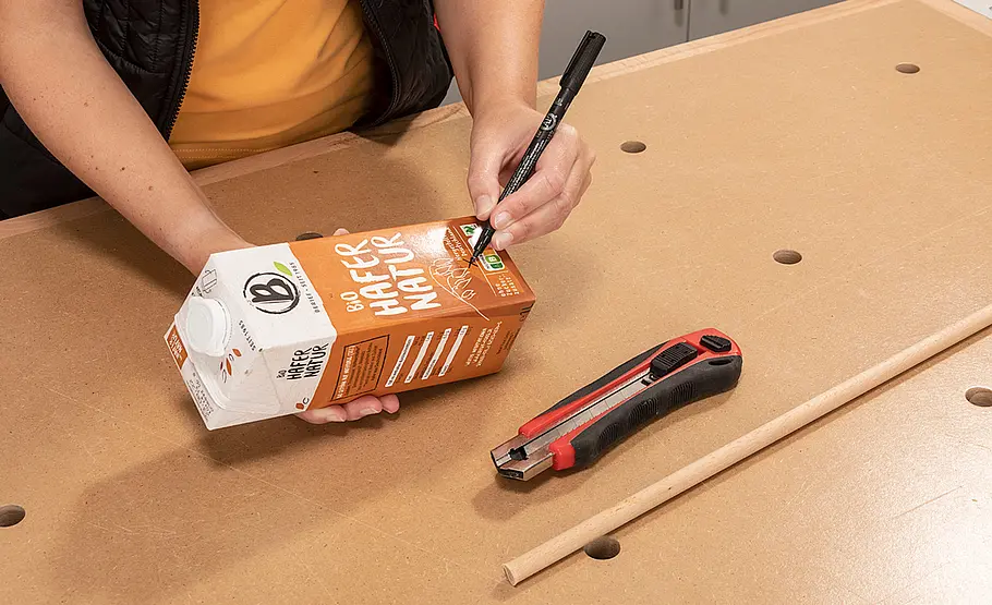 Futterspender aus Milchkarton Milchkarton wird mit einem Cuttermesser eingeschnitten