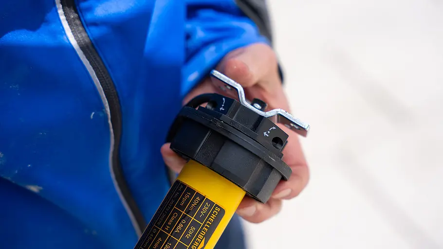 Laufringadapter aufstecken Ein schwarzer Laufringadapter ist auf das Ende eines gelben Markisenmotors aufgesteckt und wird von einer Hand gehalten.