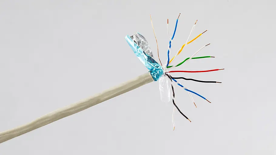 Telefonkabel mit einem Sammelsurium an Kabeln. Von oben nach unten: braun, blau und weiß ineinander verschlungen, gelb und weiß ineinander verschlungen, grün und weiß ineinander verschlungen, rot, schwarz, brau und weiß umeinander gedreht und schwarz und weiß umeinander gedreht.
