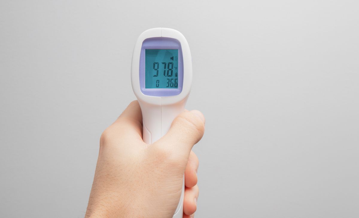 Ein Infrarot-Thermometer wird in der linken Hand gehalten.