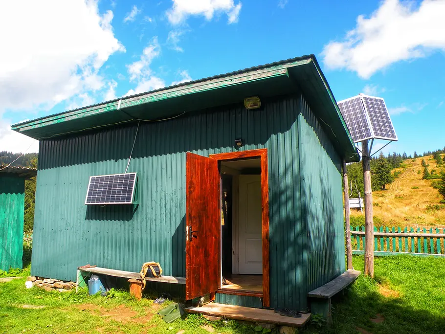 inselanlage-pv-netzunabhaengig Eine grüne Hütte wird mit Solarpanels betrieben