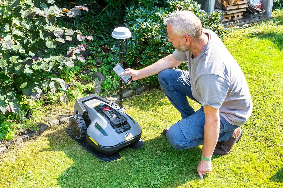 Installation per App im Garten Mann richtet im Garten mithilfe einer App den Yuka Mini 800 Mähroboter und das GPS-Modul ein.