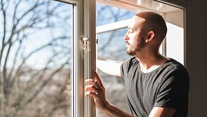 Mann öffnet Fenster um zu lüften - Foto: iStock / Luza studios