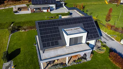 Zwei Häuser stehen in einer grünen Landschaft, auf den Dächern sind Module einer Solaranlage zu erkennen - Foto: istockphoto.com / miha vodlan